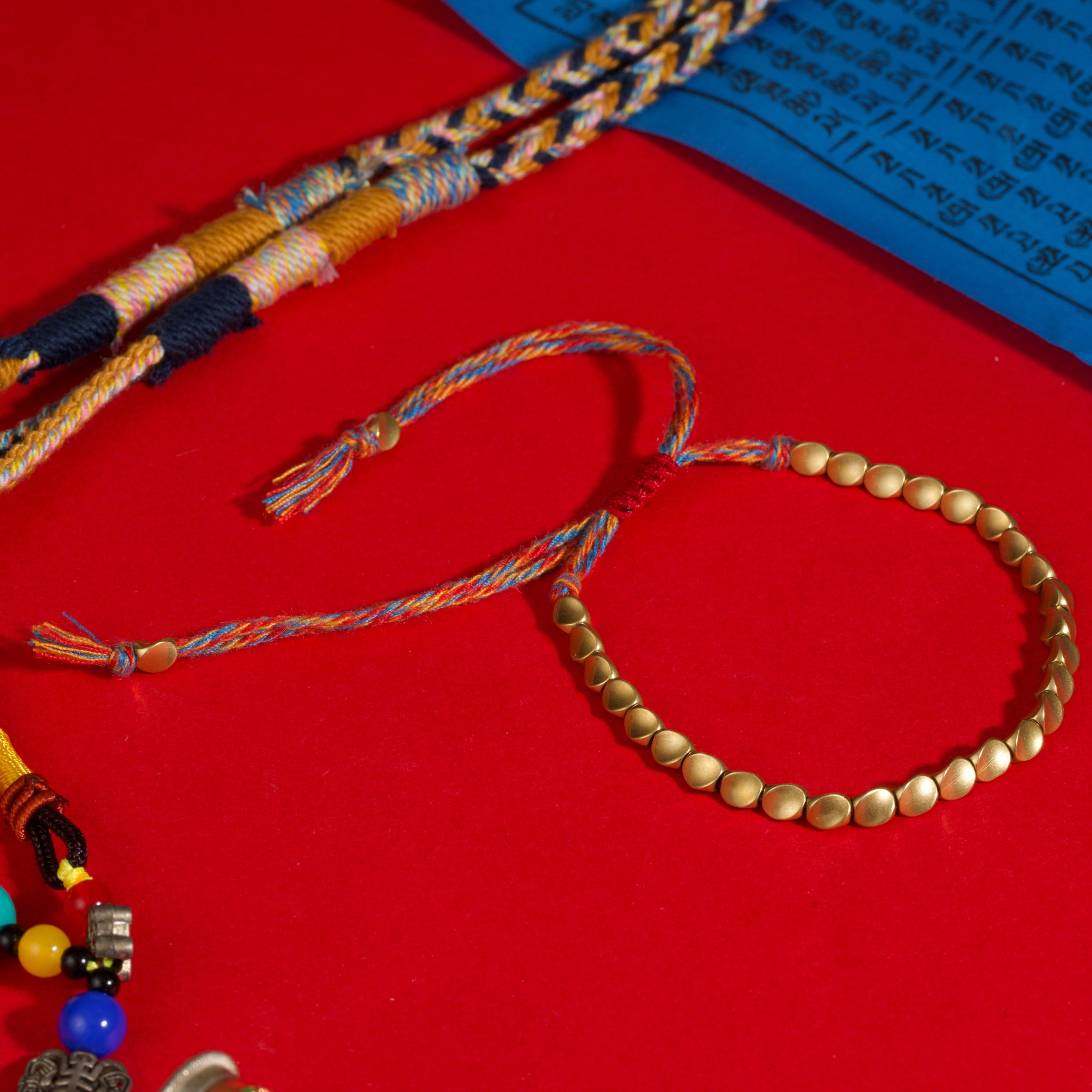 Tibetan-style red string bracelet with brass beads—metal adds weight and changes how the bracelet sits on the wrist.